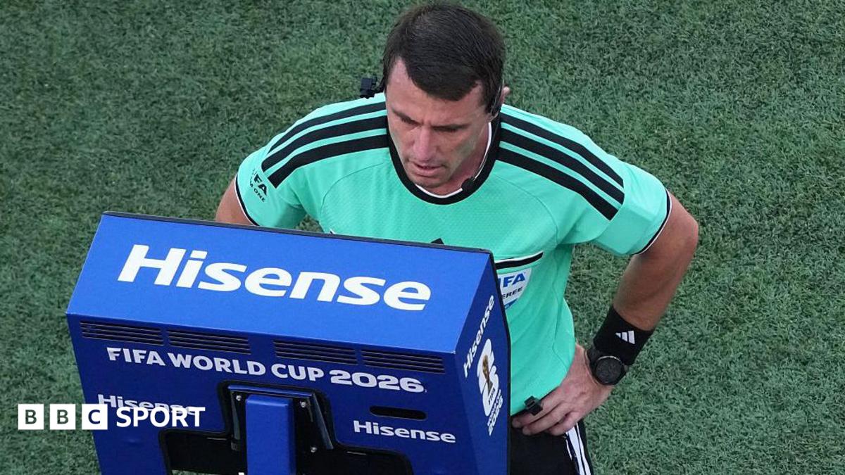 A referee looks into a blue VAR monitor