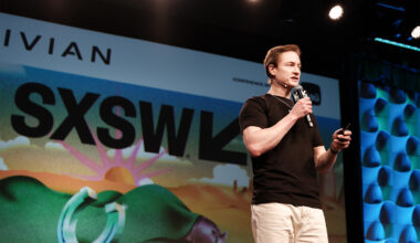 Bryan Johnson is standing on a stage and speaking into a microphone. He is wearing a black shirt.