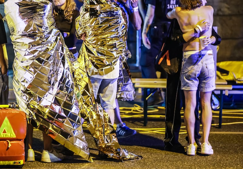 People wrapped in blankets stand near the scene where several people were injured on the sideline of the Christopher Street Day parade in Berlin, Germany. Photograph: EPA