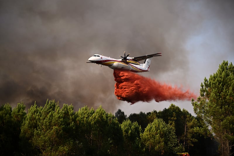 A plane releases fire retardant as it flies over a forest near Blagon. Photograph: Emma Da Silva/AP