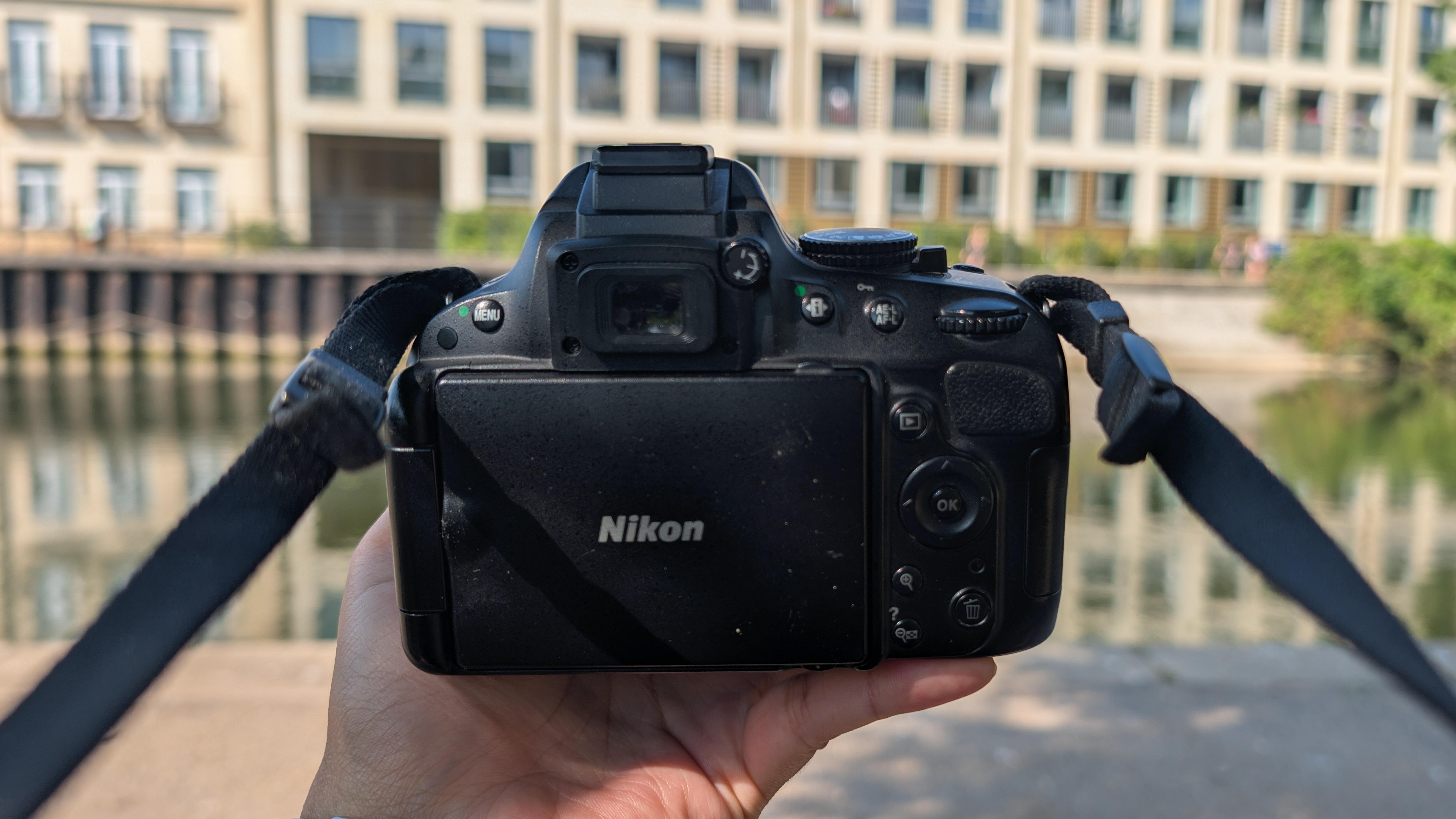 A person holding a Nikon D5100 DSLR camera