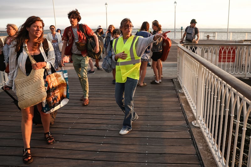A volunteer gives indication to holidaymakers from Cap-Ferret upon their arrival in Arcachon by boat during an evacuation operation. Photograph: Romain Perrocheau/Getty