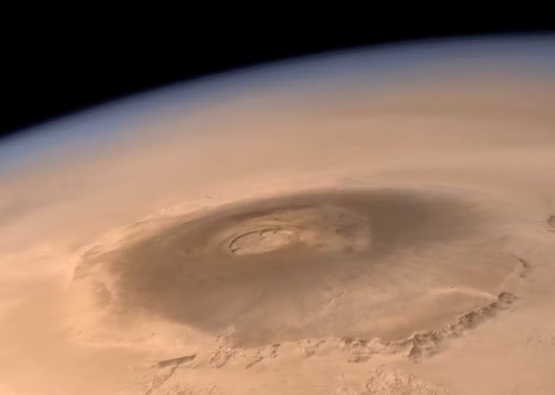 Magma systems on Mars: Oblique orbital view of a huge sprawling volcano with a big crater on reddish planet.