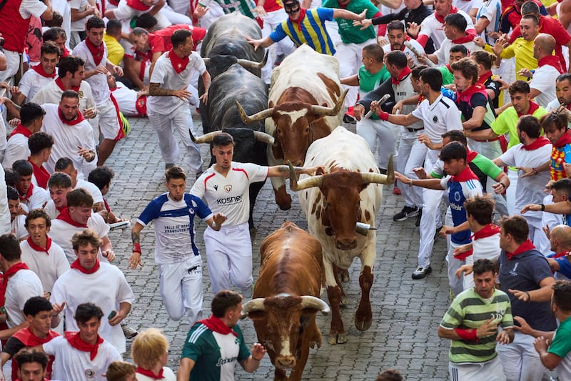 Revellers run alongside Jose Escolar’s fighting bulls during the fifth running of the bulls in Pamplona. Photograph: Miguel Oses/AP
