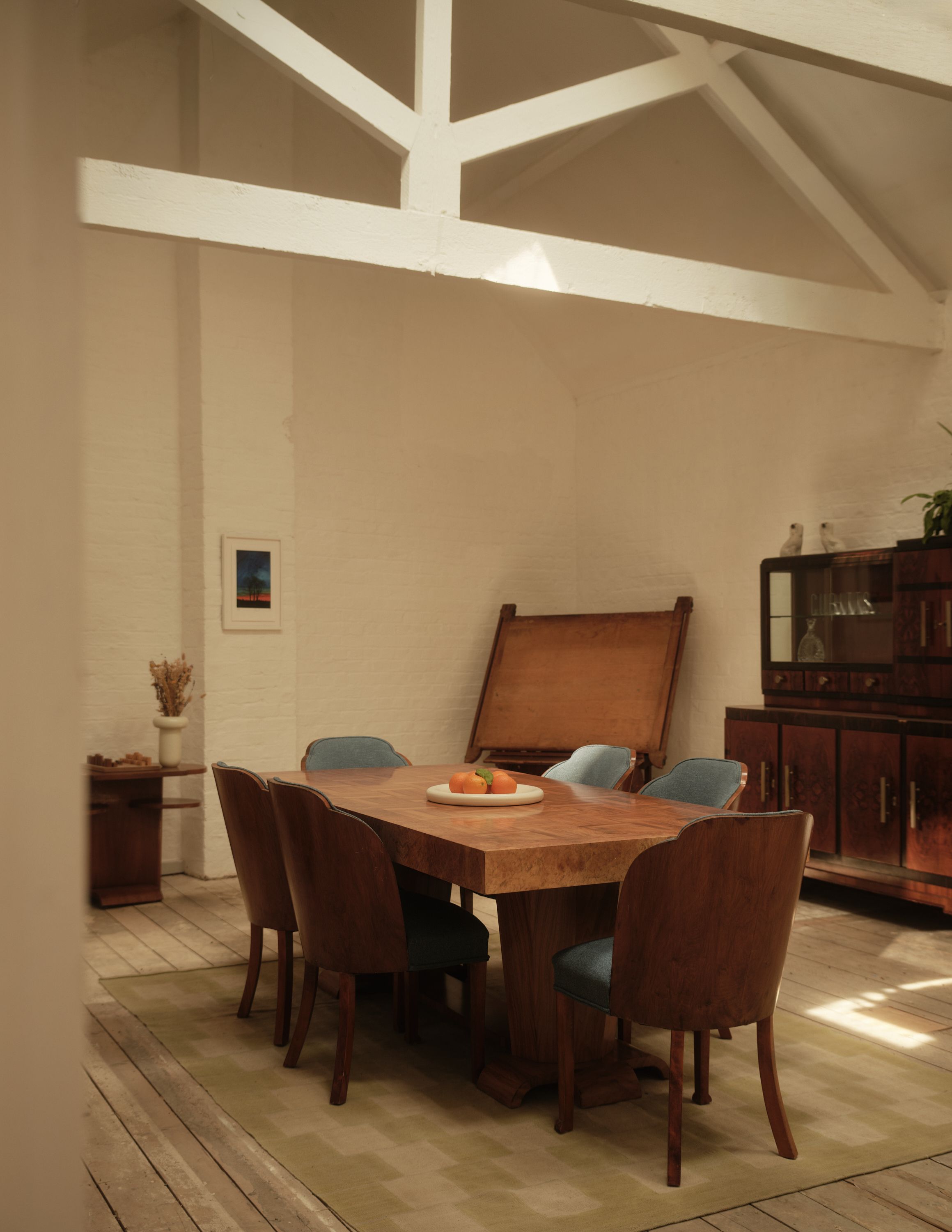 A warmly decorated former warehouse now filled with mid-century modern wooden furniture, colorful pops across floors and walls, statement lighting, glass blocks, and plants.