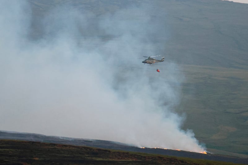 A helicopter drops water on fires that have broken out in the Dublin Mountains
