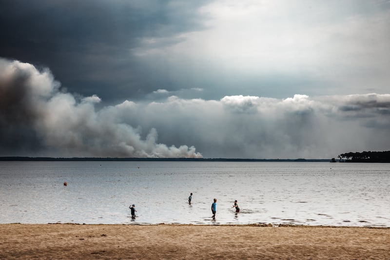 Children swim at a beach while a large smoke plume from a distant wildfire rises across the water in Le Porge, France on Saturday. Photograph: David Sepeau/Hans Lucas/AFP via Getty Images