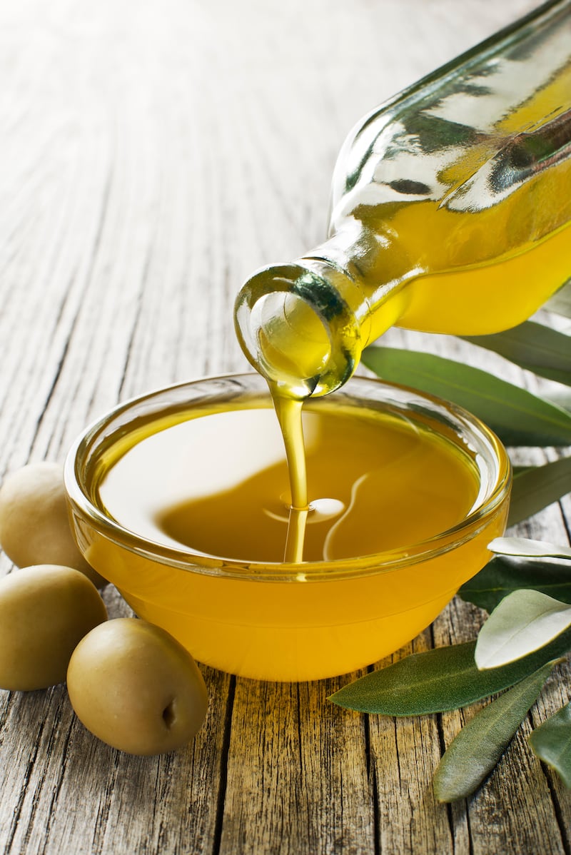 Pouring a bottle of extra virgin olive oil in a bowl