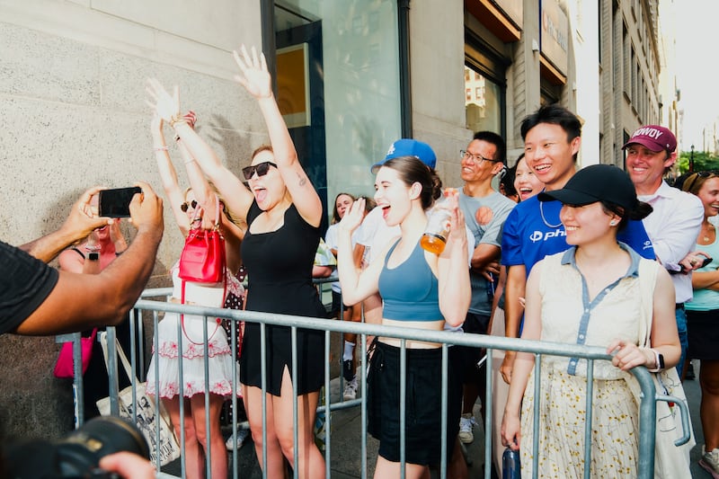 Taylor Swift fans cheer behind a barricade near Madison Square Garden ahead of the wedding event. Photograph: Lanna Apisukh/The New York Times
                      