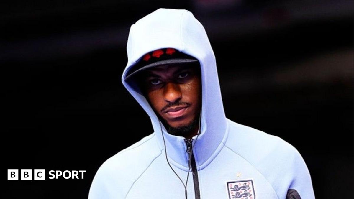 Marcus Rashford wearing a white England zip-up top, hood pulled up over his head