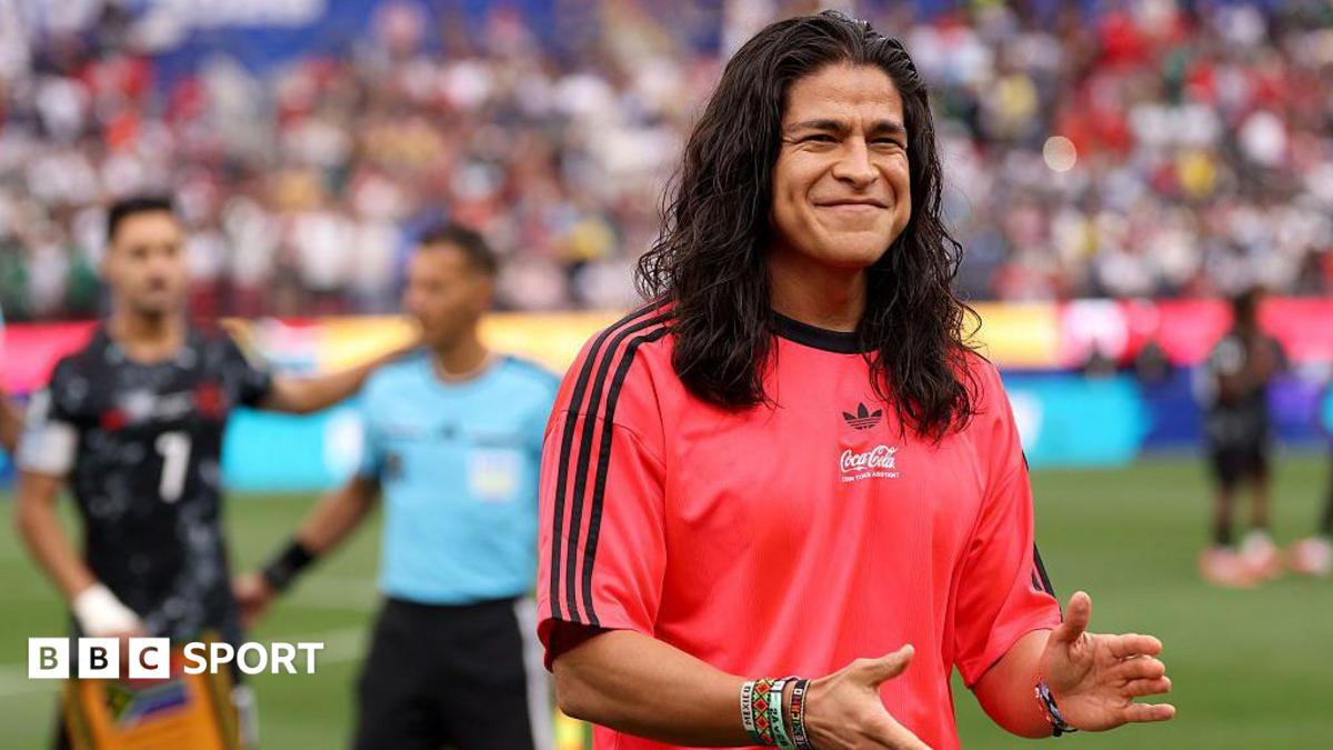 Cristo Fernandez smiling and clapping his hands while wearing a red Adidas t-shirt