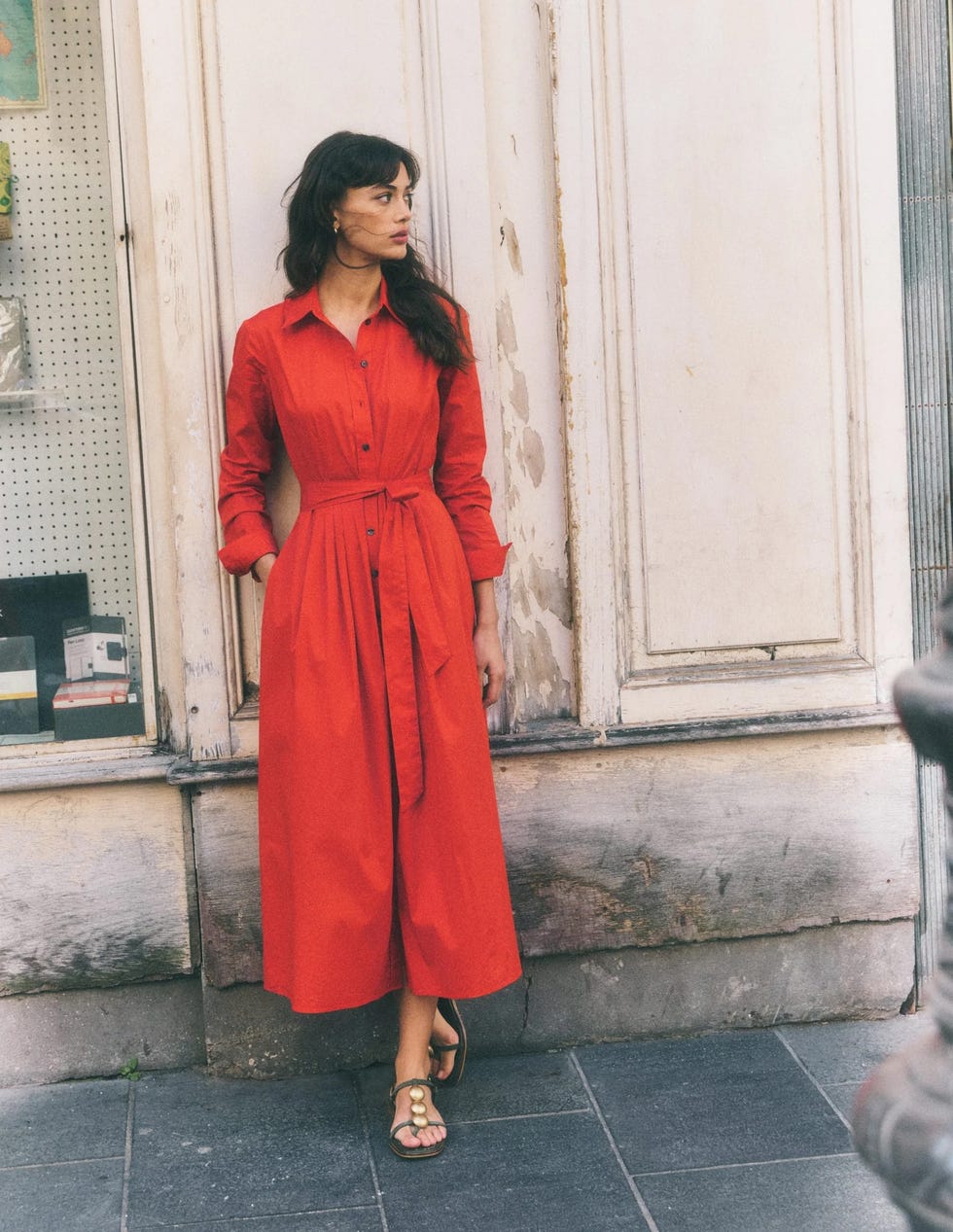 woman in a long red dress standing by a weathered wall. woman in a long red dress standing by a weathered wall.