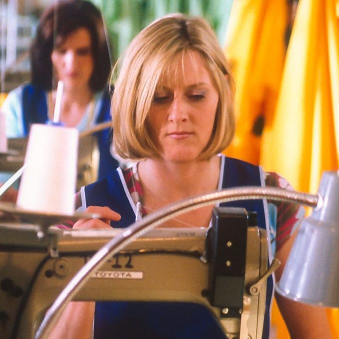 woman sewing in a garment factory with yellow fabric in the background woman sewing in a garment factory with yellow fabric in the background