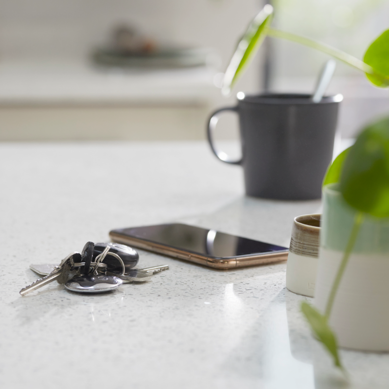 things-to-remove-from-counters keys a smartphone a mug and a small plant on a countertop