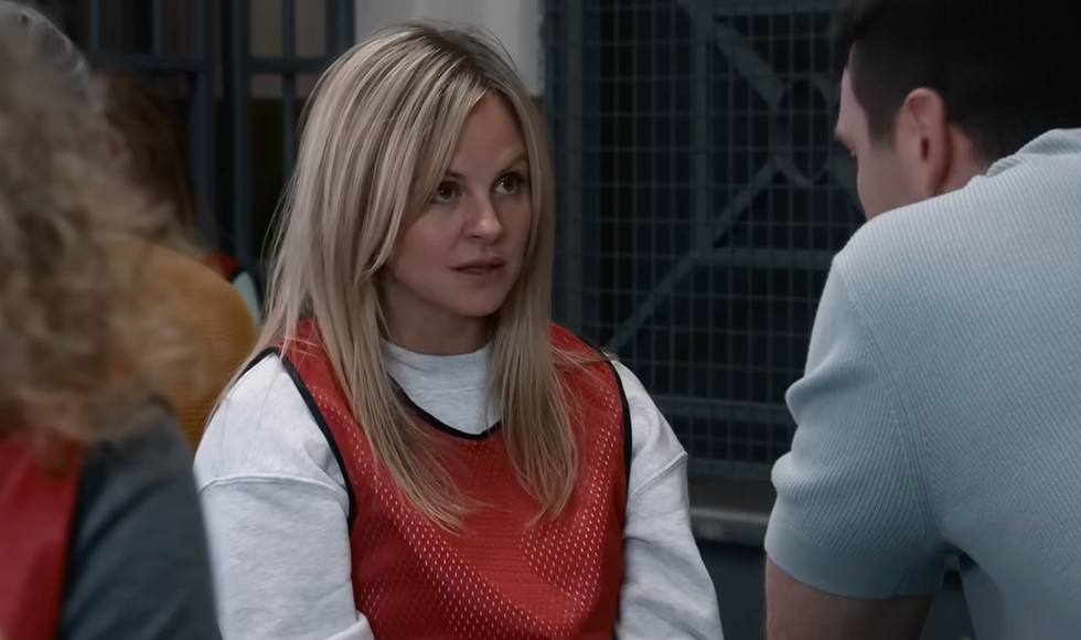 two people conversing, one woman in a red vest sitting across from a man. two people conversing, one woman in a red vest sitting across from a man.