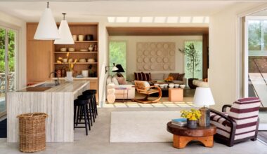 an open plan poolhouse with patio doors, a small oak and marble kitchen and layered striped and vintage wooden interiors