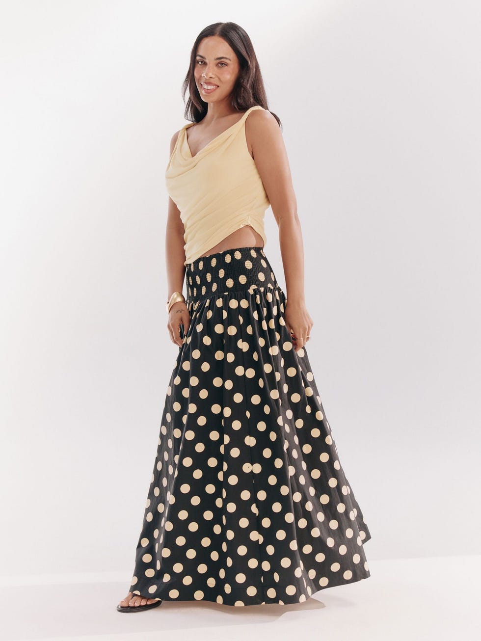 Woman wearing a yellow top and polka dot skirt smiling in a studio setting. woman wearing a yellow top and polka dot skirt smiling in a studio setting.