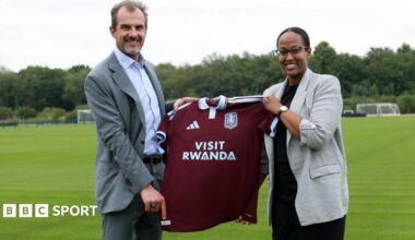 Aston Villa president of business Francesco Calvo and Janet Karemera, CEO of the Rwanda Convention Bureau, hold up an Aston Villa shirt with Visit Rwanda as sponsor