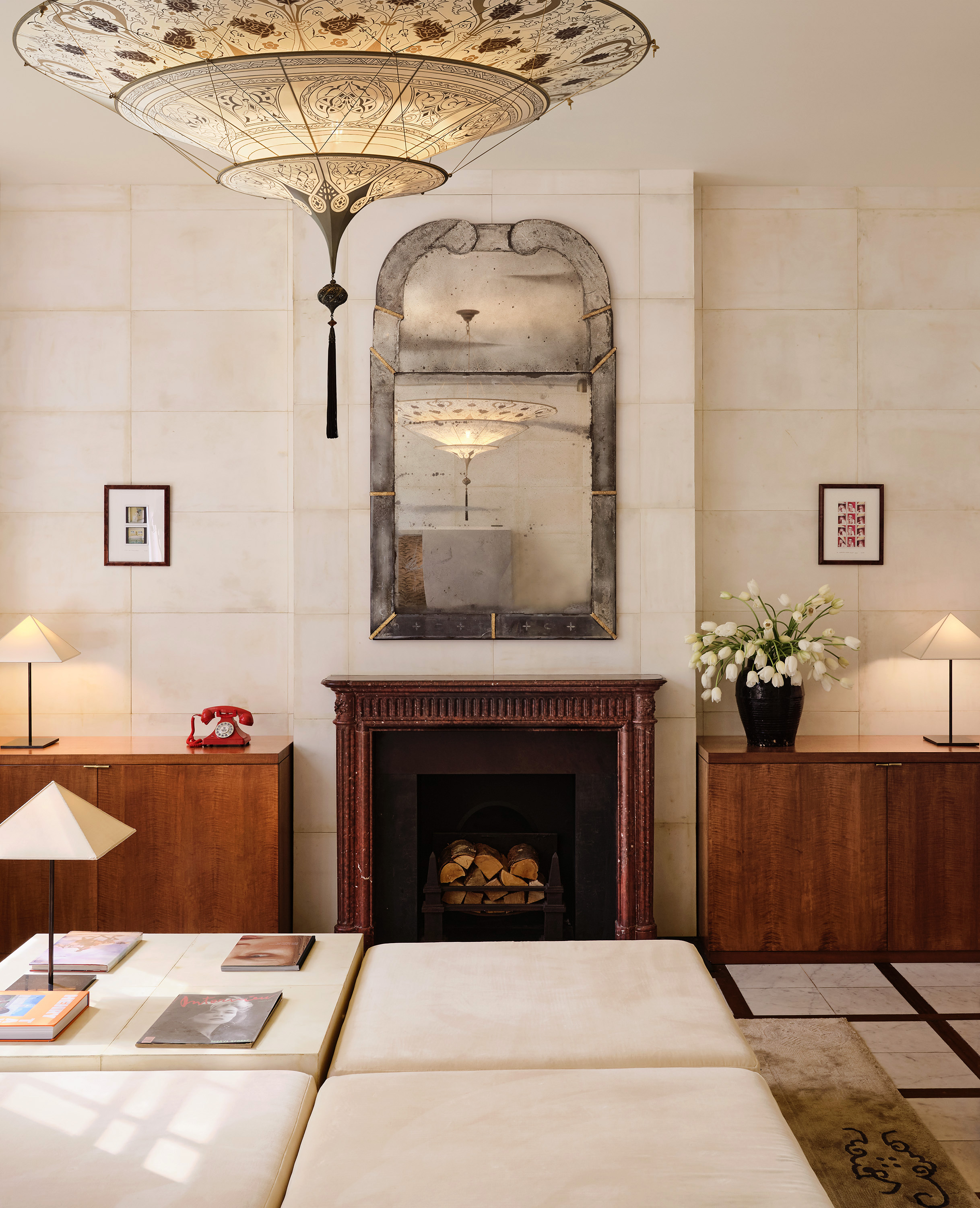 The glossy, curated interiors of a fashion boutique inspired by Italian design and architecture, with marble surfaces, statement chandeliers, and artsy separes interspersed with eye-catching clothing.