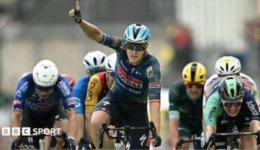 Tim Merlier celebrates winning stage 12 by raising a finger into the air