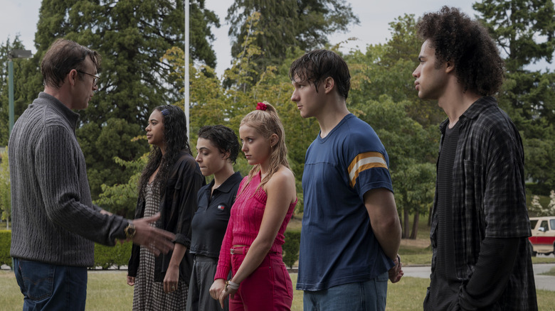 Chandler Kinney as Kimberly, Gabrielle Policano as Liz, Lexi Minetree as Elle, Jacob Moskovitch as Miles, and Zac Looker as Dustin, all standing outside on a grassy lawn, listening intently to Matt Oberg as Principal Anderson in 