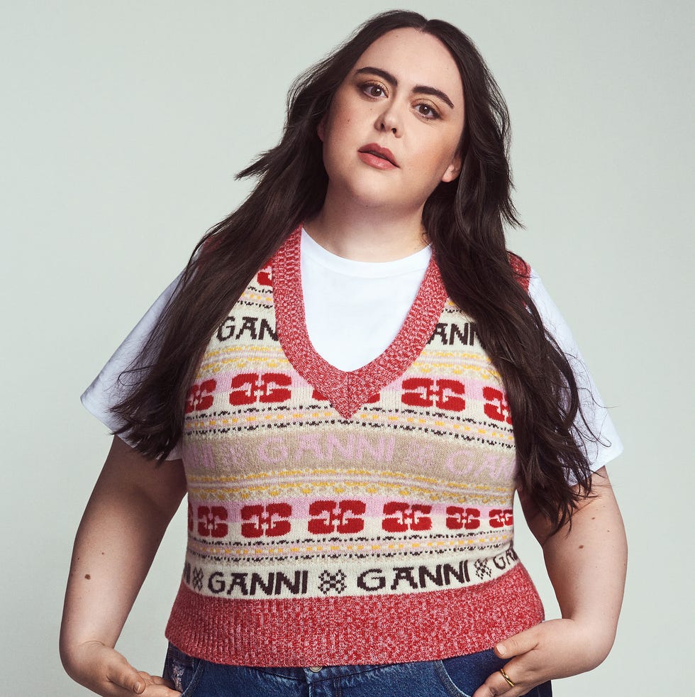 Person wearing a colorful Ganni sweater vest over a white t-shirt. Person wearing a colorful Ganni sweater vest over a white t-shirt.