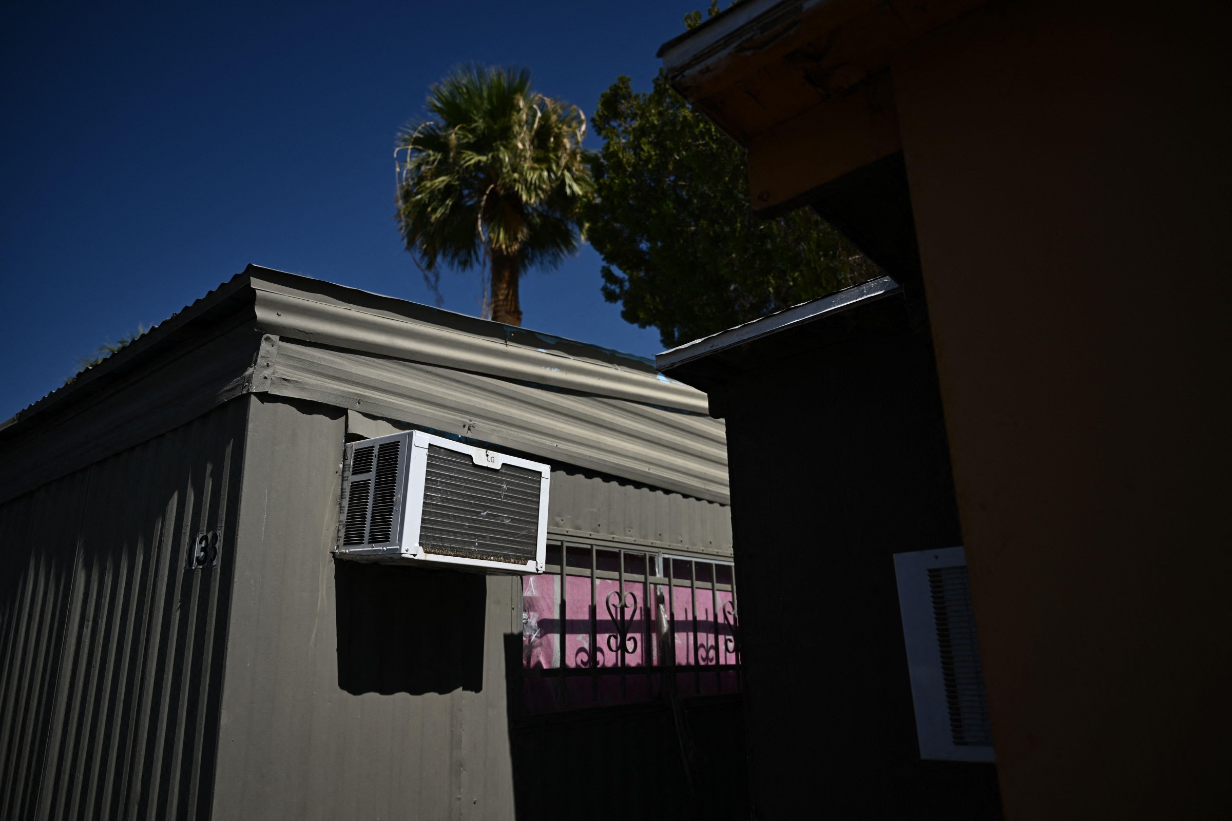A window mounted air conditioning unit hangs outside a mobile home during a record heat wave in Phoenix