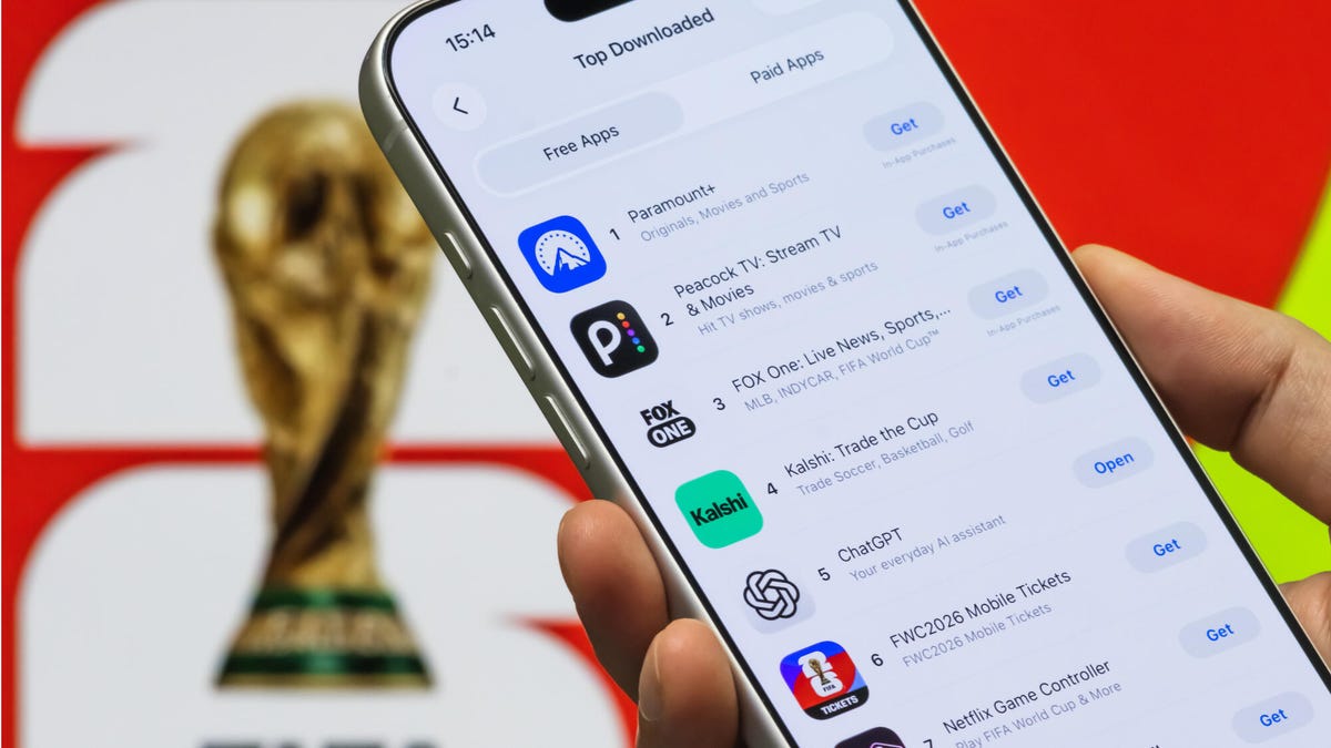 A mock-up image of someone holding a phone looking at Apple App Store's Top Free Apps in front of a poster featuring the FIFA World Cup trophy in the background.