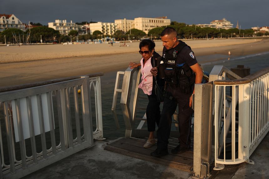 A police officer helps a holidaymaker from Lege-Cap-Ferret as she arrives in Arcachon by boat during the evacuation on Friday.