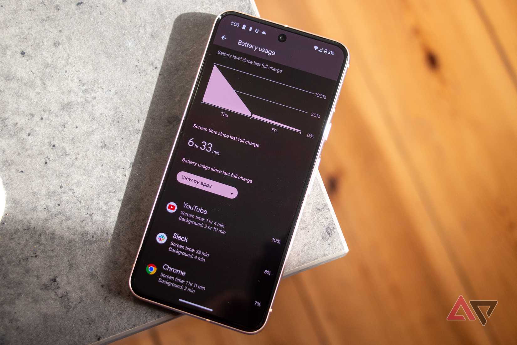 A Pixel 8 with battery app open resting on edge of grey table