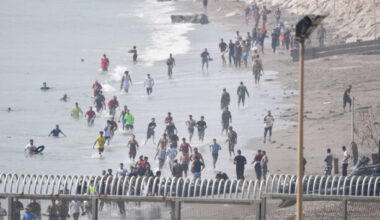 Hundreds of people swim round barriers and enter North African Spanish territory from Morocco