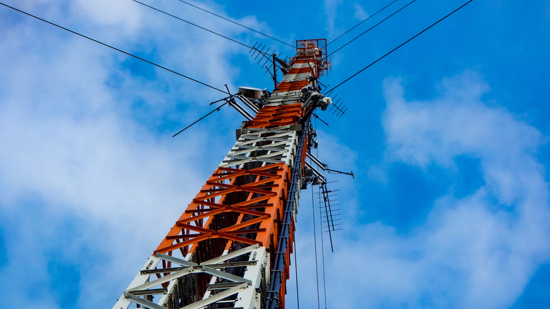 View looking up at the top of a radio broadcast tower in red and white.