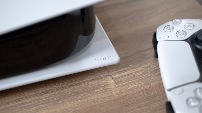 The corner of a Sony PlayStation 5 console and controller are shown with the Sony logo
