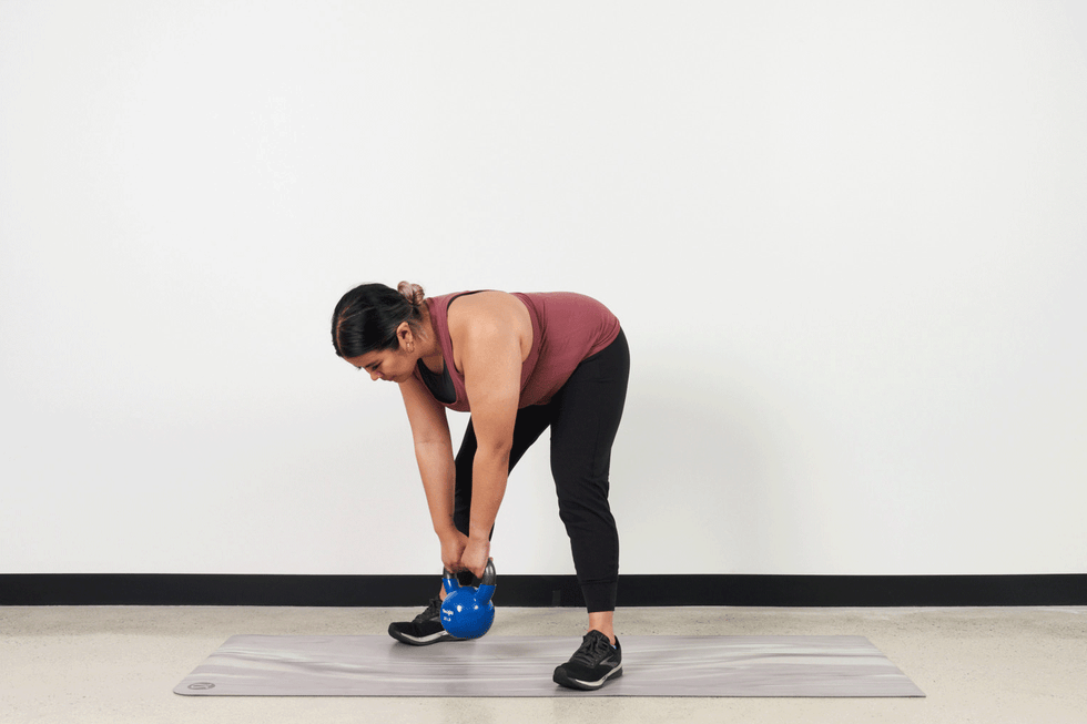 individual performing a kettlebell deadlift on a yoga mat