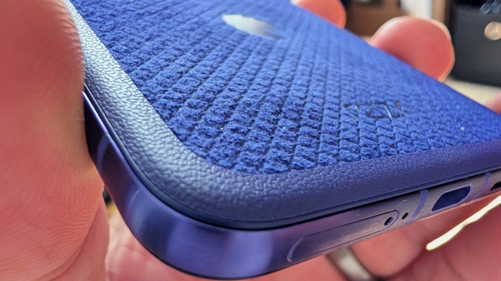 Close-up of a blue textured smartphone case held in a hand with focus on its edges and buttons.