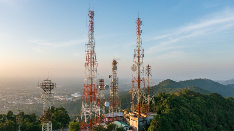 Telecommunications towers on a mounting with the sun setting nearby.