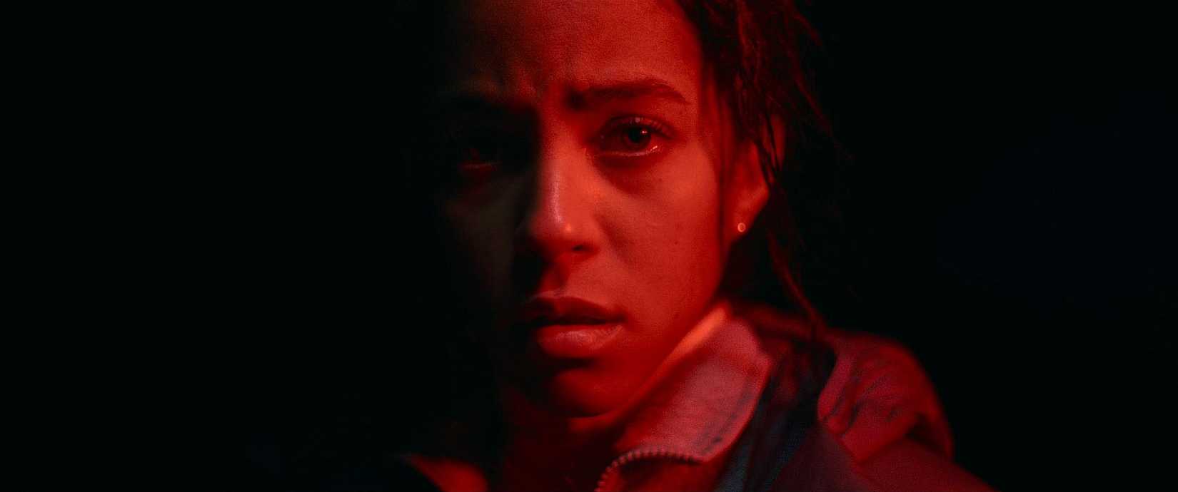 Lou Llobell covered in red light in the movie Passenger