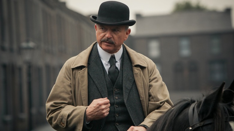 Sam Neill as Major Chester Campbell, wearing a cap while riding a horse in Peaky Blinders