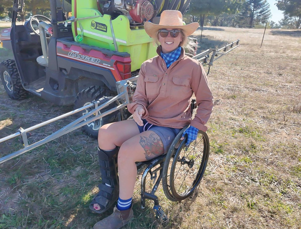 woman in a wheelchair next to a Polaris Ranger side by side agricultural vehicle with spray apparatus on the back.