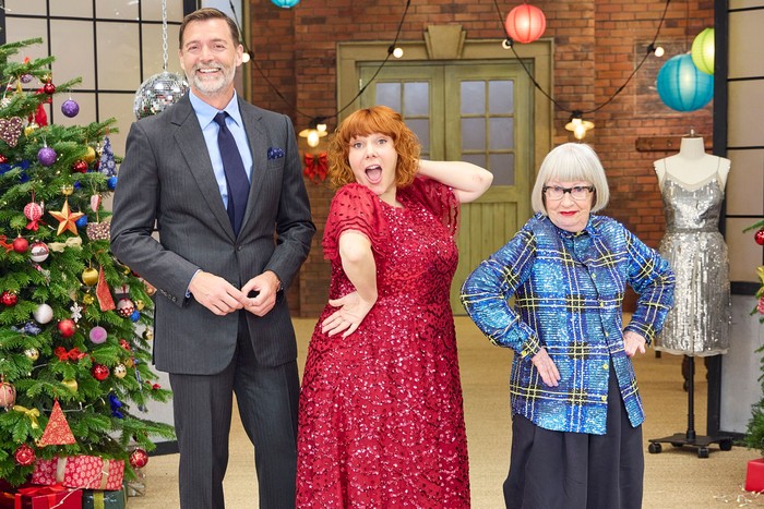 sewing bee Patrick Grant, Sophie Whelan and Esme Young stood in a row smiling and posing ahead.