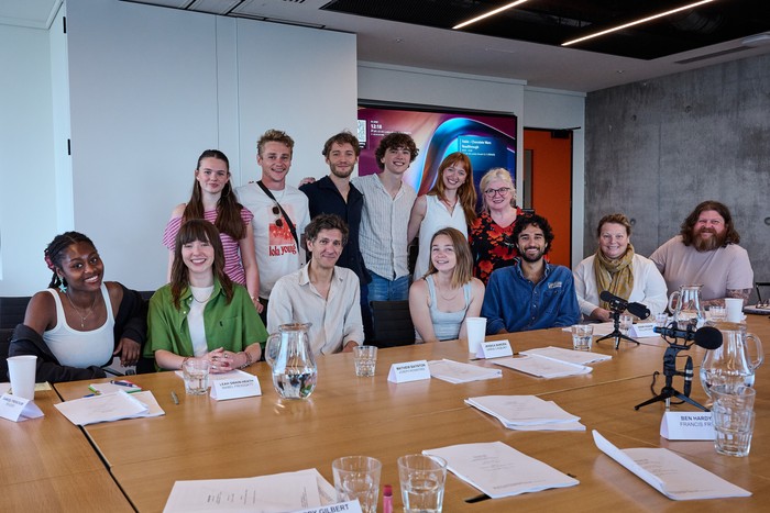 The Cadburys Full Cast The entire cast of The Cadburys pose together in front of a brown table littered with scripts. Five are sitting down, while six are standing behind them, and they're all smiling