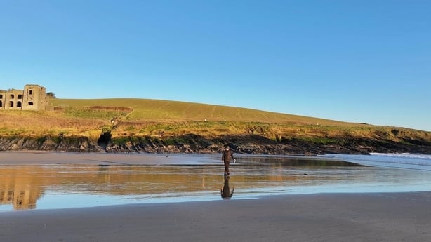 man standing on a beach with a castle in the background