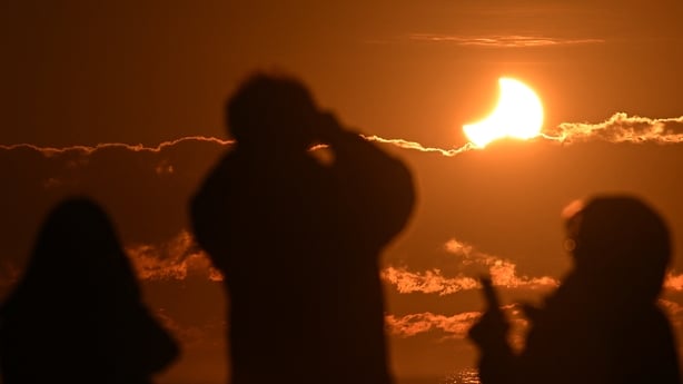 People watch a partial solar eclipse at New Brighton, a coastal suburb of Christchurch, on September 22, 2025. A solar eclipse occurs when the moon passes between Earth and the sun, casting a shadow on our planet. The sun appeared as a crescent due to this partial eclipse. In New Zealand, coverage r