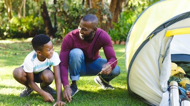 father and son pitching tent in garden. 