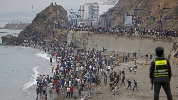 People gather along the fence at the site of clashes near Fnideq, on the Morocco-Spain border