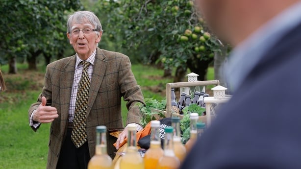 Man talking to another man off camera beside bottles of apple cider