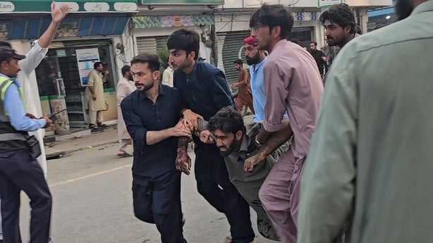 Three people carry away an injured victim following a suicide bombing during a protest in Pakistan's Swat district on August 2, 2026