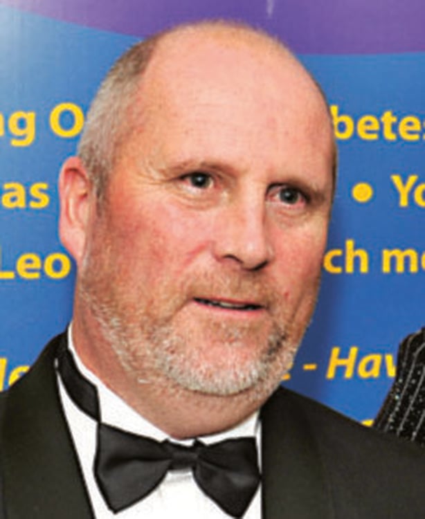 Middle aged, balding white man with stubble wearing a dickie bow