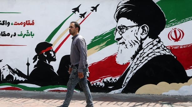 A man walks in front of a wall mural as daily life continues amid ongoing tensions between the United States in Tehran, Iran