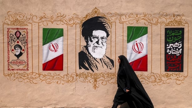 A woman walks past a mural depicting Iran's late supreme leader Ali Khamenei at Valiasr Square in central Tehran on August 8, 2026